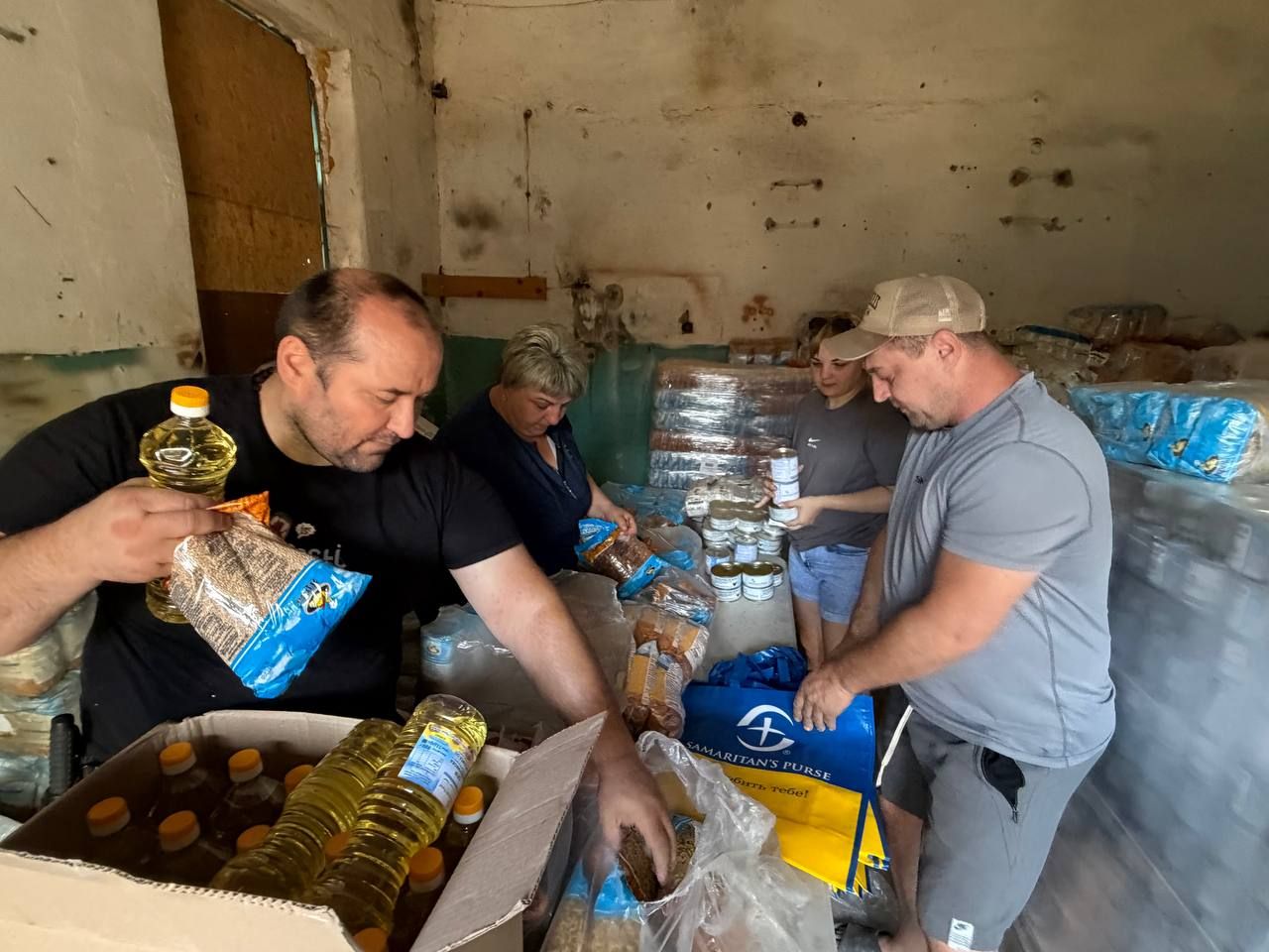 Команда складає олію, крупи і консерви в продуктові набори на складі