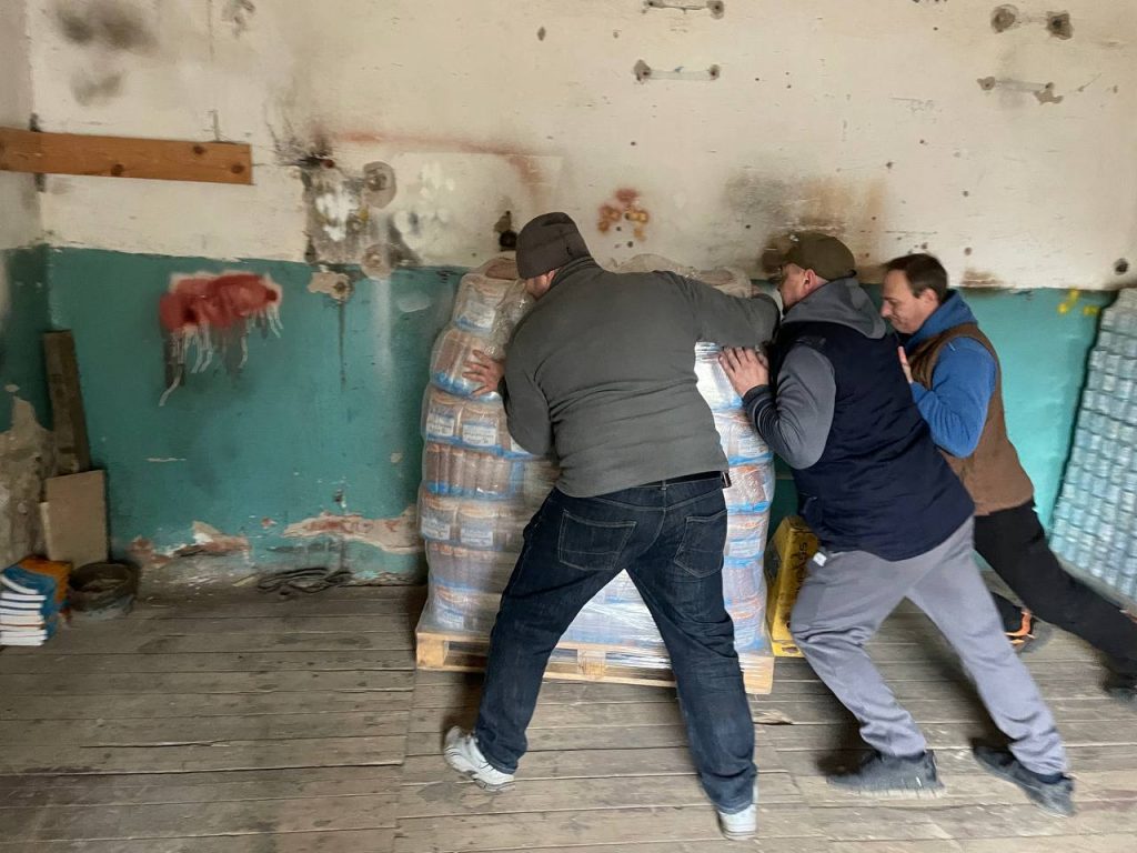 Команда переміщує запаковані продукти до приміщення гуманітарного складу