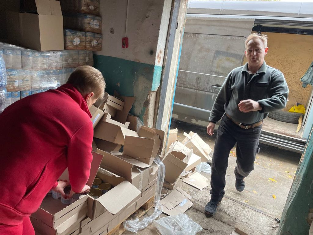 Команда готує коробки з продуктами біля відкритого мікроавтобуса