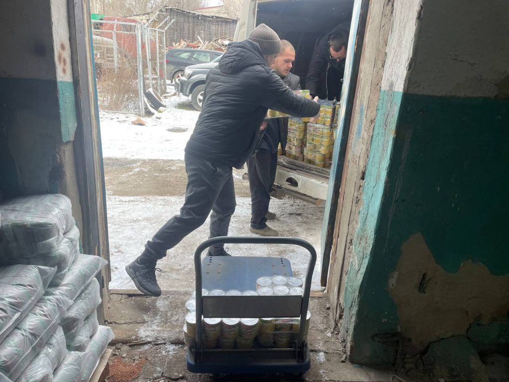 Працівник передає упаковки продуктів із машини до складу