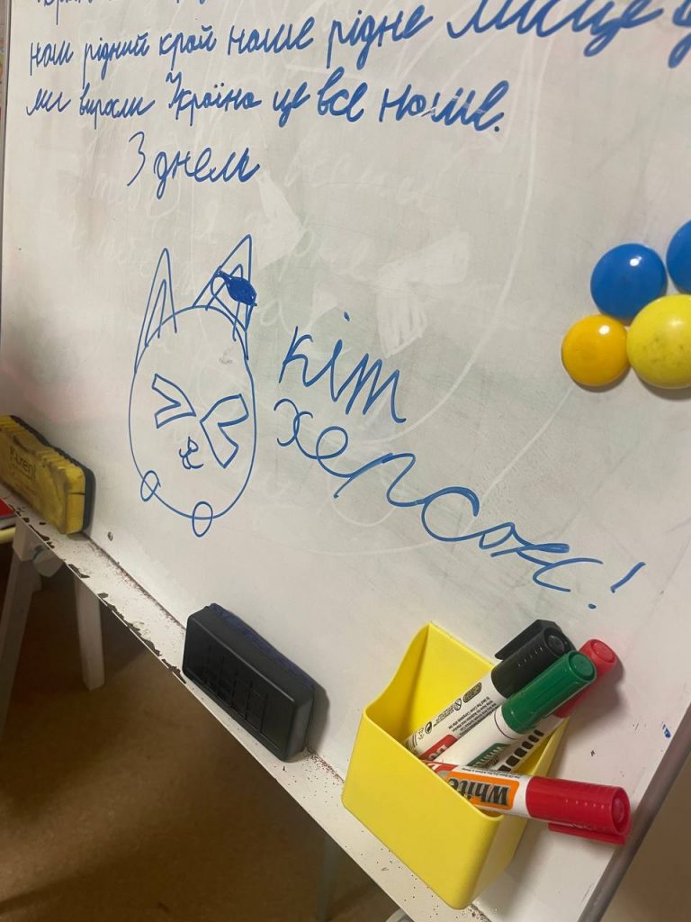 Дитячі малюнки котів і святкові побажання на дошці