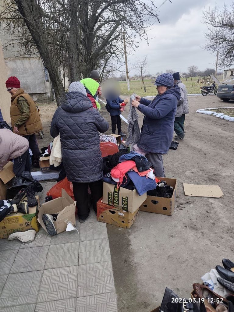 Загальний план передачі одягу біля коробок на вулиці
