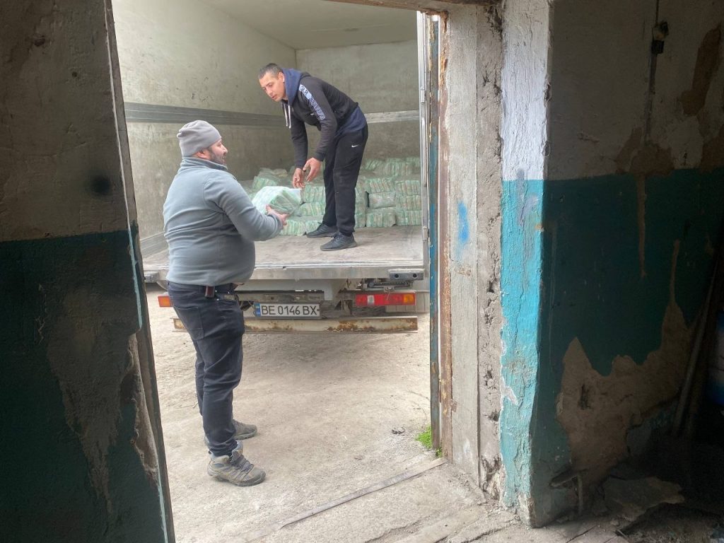 Чоловіки передають запаковані продукти через відкриті двері складу
