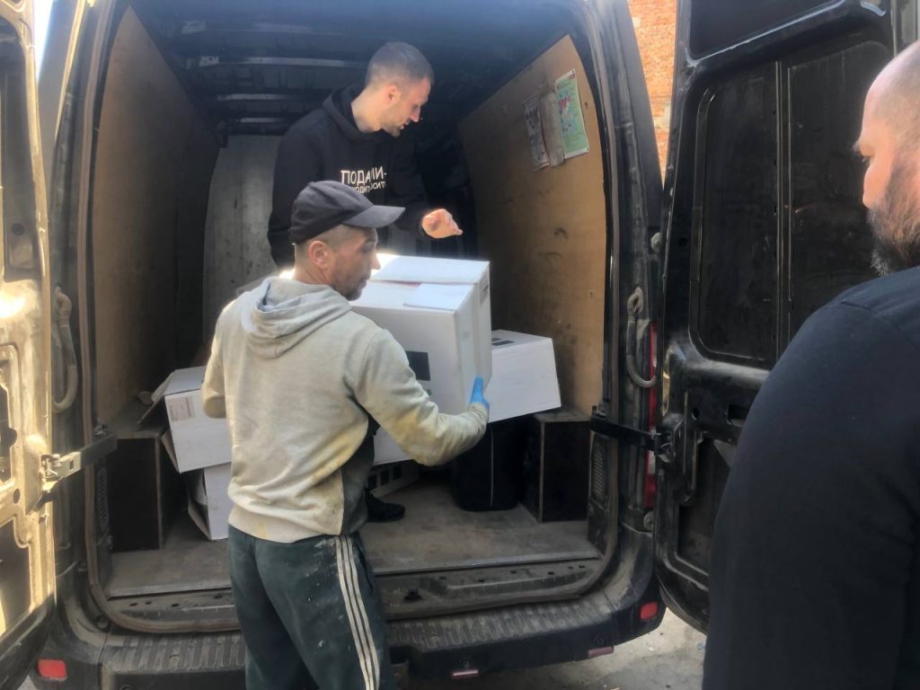 Команда переносить коробки з мікроавтобуса до гуманітарного складу