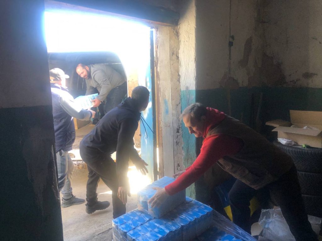 Команда розвантажує упаковки продуктів біля відкритих дверей складу