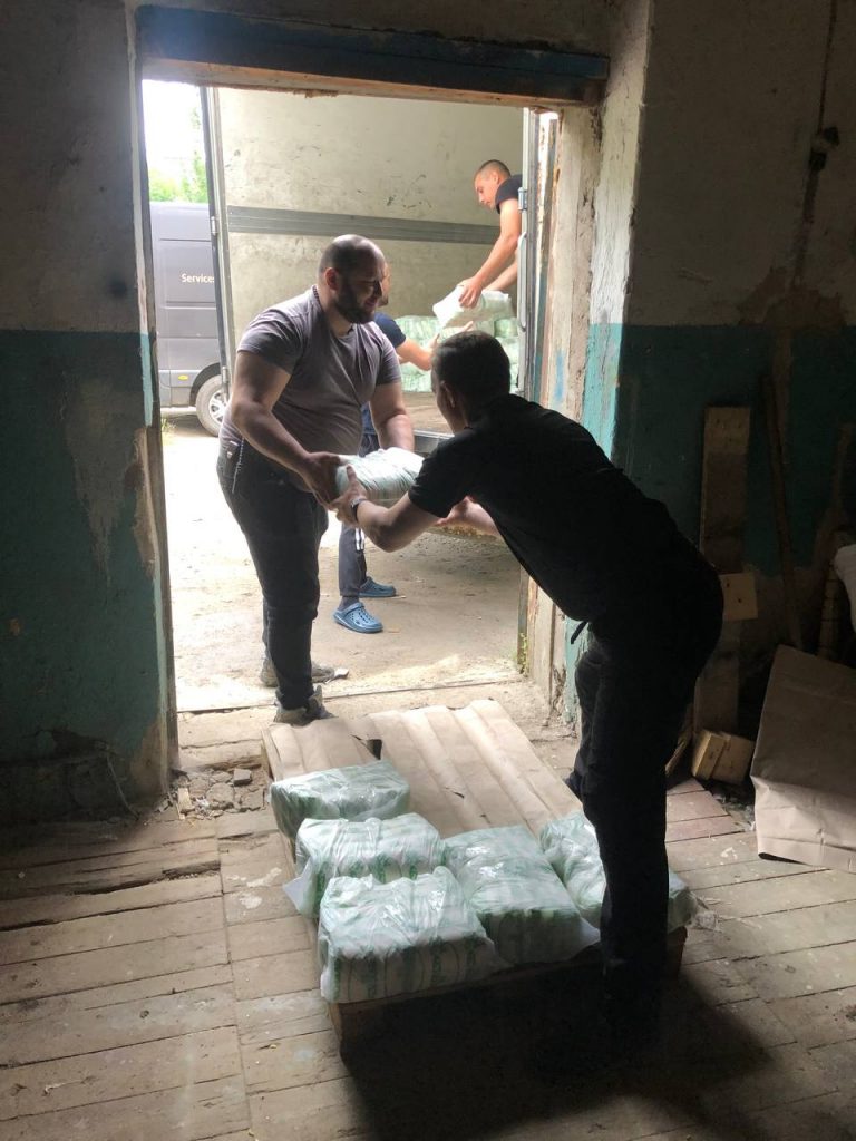 Команда передає упаковки продуктів від автомобіля до складу