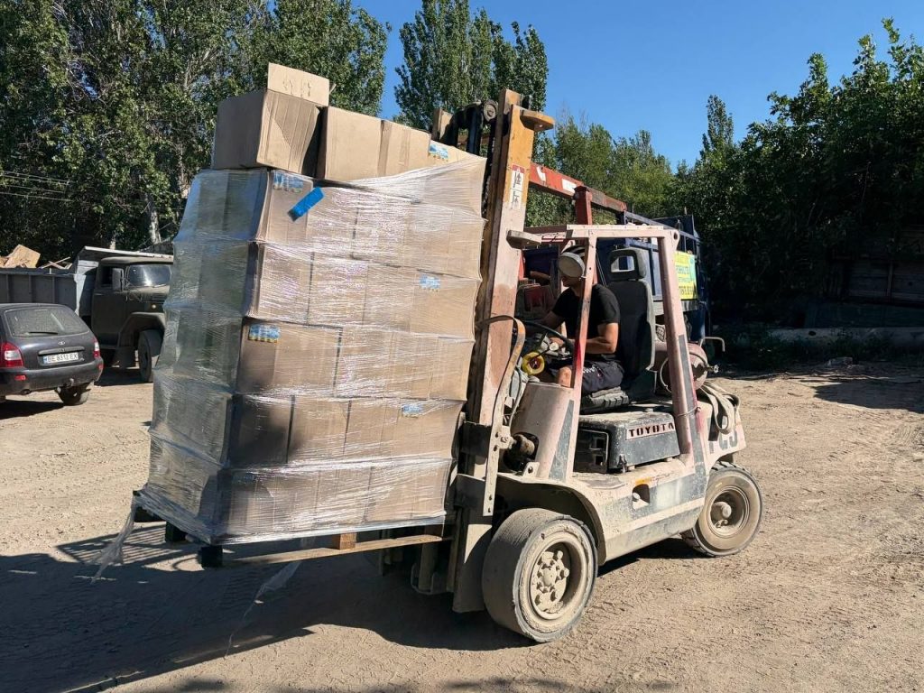 Навантажувач перевозить палету з коробками продуктів біля складу